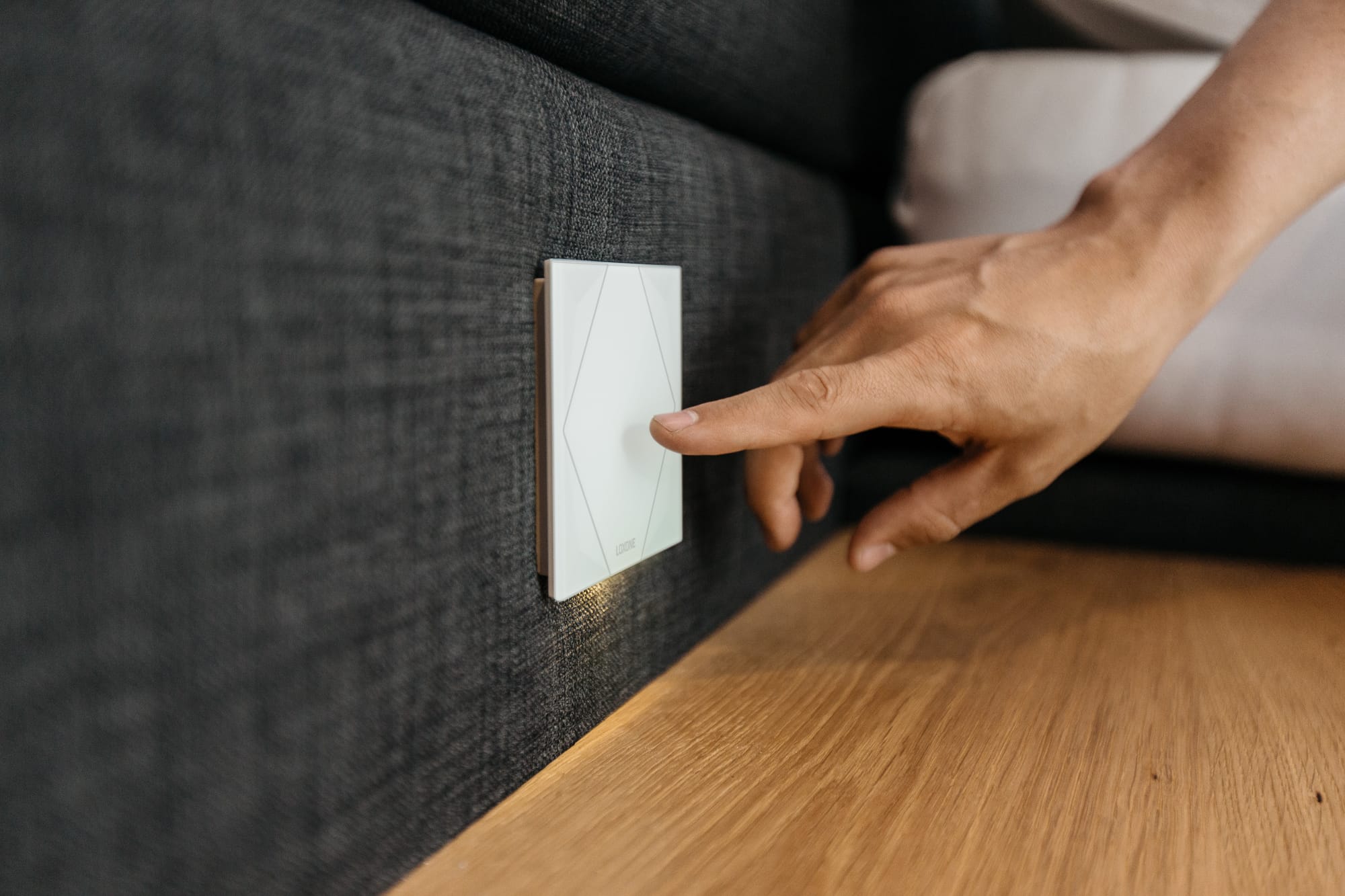 A hand using a wall switch that also controls scenes